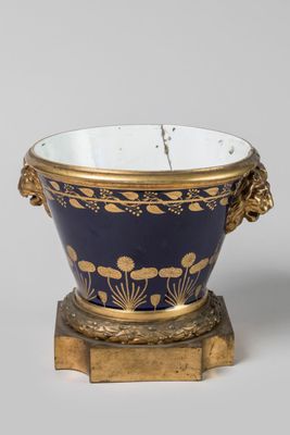 a close up of a blue and gold bowl on a wooden stand