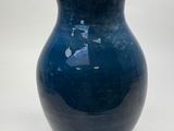 a blue vase that is sitting on a white surface