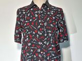 Le t-shirt est noir, avec des flèches rouges et blanches dessus.