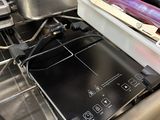 une cuisinière avec une casserole posée dessus, dans une cuisine