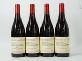 four bottles of wine are lined up on a white surface