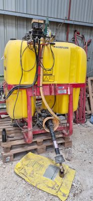 un réservoir jaune posé sur une palette, auquel est raccordé un tuyau