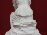 a white statue of a woman sitting on top of a table