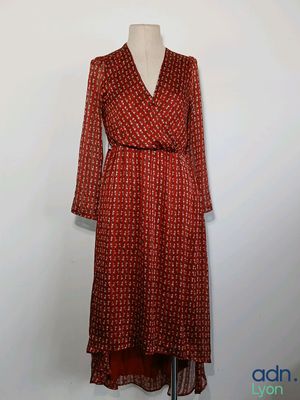 une robe rouge posée sur un mannequin, devant un mur blanc