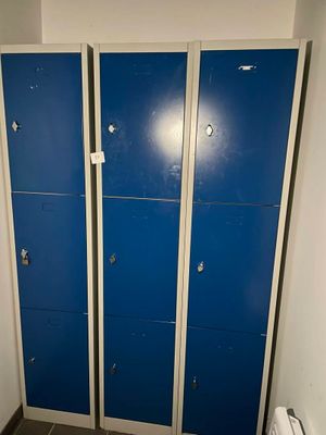 trois casiers bleus dans une salle de bains, à côté des toilettes