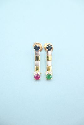 a pair of earrings with multi colored stones on a blue surface