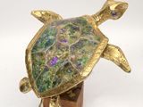 brass turtle figurine with multicolored glass eyes on a wooden base