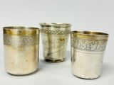 trois coupes en argent ornées de motifs, posées sur une surface blanche