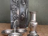 un vase en argent et deux plats en argent posés sur une table