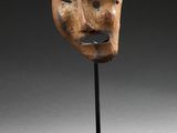 a wooden mask on a stand with a black base