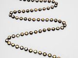 a close up of a gold beaded necklace on a white surface