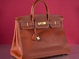 a brown leather handbag sitting on top of a table next to a red wall