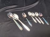 six cuillères en argent sont alignées sur une nappe noire