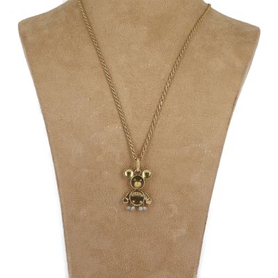 un gros plan sur un collier orné d'un ours en peluche, porté par un mannequin