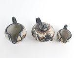 three pieces of pottery sitting on a white surface