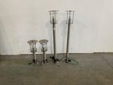 three different types of stainless steel floor lamps on a concrete floor