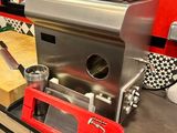 cafetière en acier inoxydable posée sur le plan de travail de la cuisine, avec des placards rouges