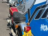 une moto rouge garée devant un bus bleu et blanc