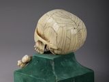 an image of a carved skull on a green pedestal