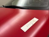 a red car with a sticker on the hood of it