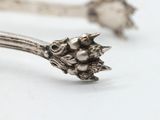 a silver spoon with a flower on it on a white surface
