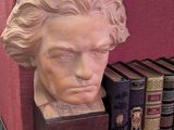 un buste d'homme assis sur une étagère avec des livres