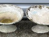 two cement bowls sitting next to each other on the ground