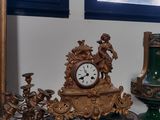 trois vases et une horloge posés sur une étagère devant une fenêtre