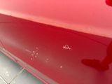 a close up of a red car with scratches on it