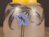 a glass vase with a blue flower on it on a table
