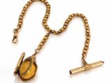 an image of a gold necklace with a tiger ' s eye on it