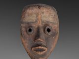 a close up of a wooden mask on a gray background