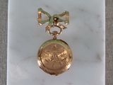 une petite montre de poche en or ornée d'un nœud