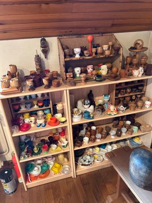 une pièce avec une étagère remplie de poteries et d'autres objets