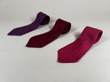 three different colored ties on a white surface with a white background