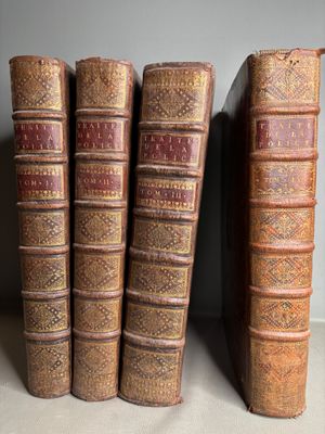 several old books are lined up on a shelf next to each other