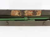 une vieille pipe verte dans un étui en métal posé sur une surface blanche