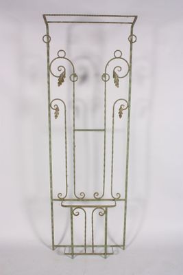 an iron plant stand with a glass door on top of it