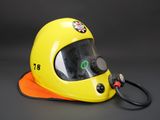 yellow helmet with a gas mask attached to it on a black background