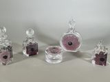 quatre bouteilles en verre contenant des fleurs roses et noires, posées sur une surface blanche