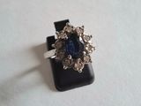 gros plan d'une bague avec une pierre bleue entourée de diamants blancs