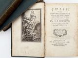 un livre ouvert posé sur une table à côté d'une pile de livres