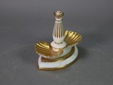 a white and gold vase with a shell on top of it