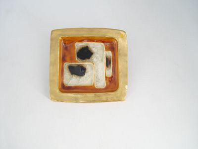 un objet de forme carrée, de couleur marron et noire, posé sur une surface blanche