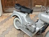a silver motor scooter parked in front of a wooden door