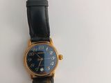 an image of a black and gold wrist watch on a white surface