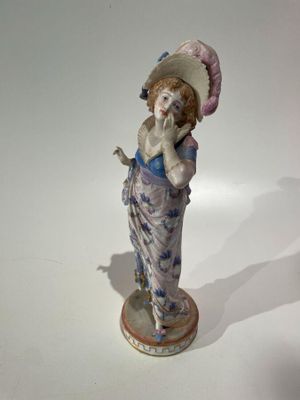 a figurine of a woman wearing a hat and dress