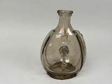 un vase en verre muni d'une poignée en argent, posé sur un fond blanc