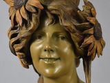 bronze statue of a woman with a sunflower in her hair and a bird on her head