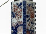 un vase bleu et blanc posé sur un socle surmonté d'une lampe
